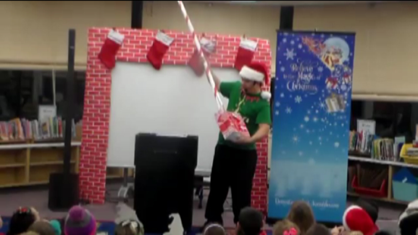 Christmas school assembly performer Cris Johnson holding a large candy cane
