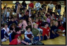 children watching School Assembly Presenter Cris Johnson performing a magic trick