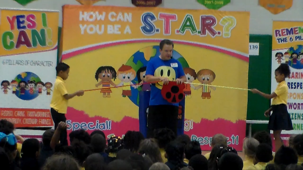 school assembly presenter Cris Johnson at a character education show with 2 volunteers